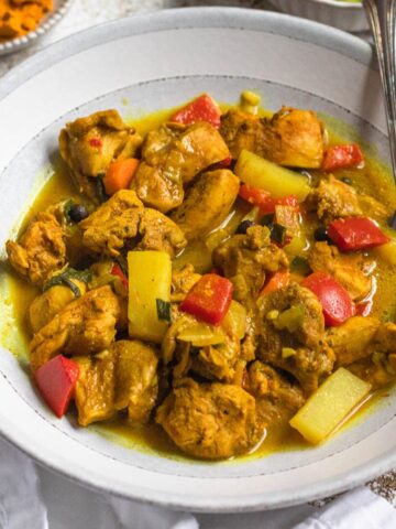 Bowl of Jamaican chicken curry with a fork resting in it.