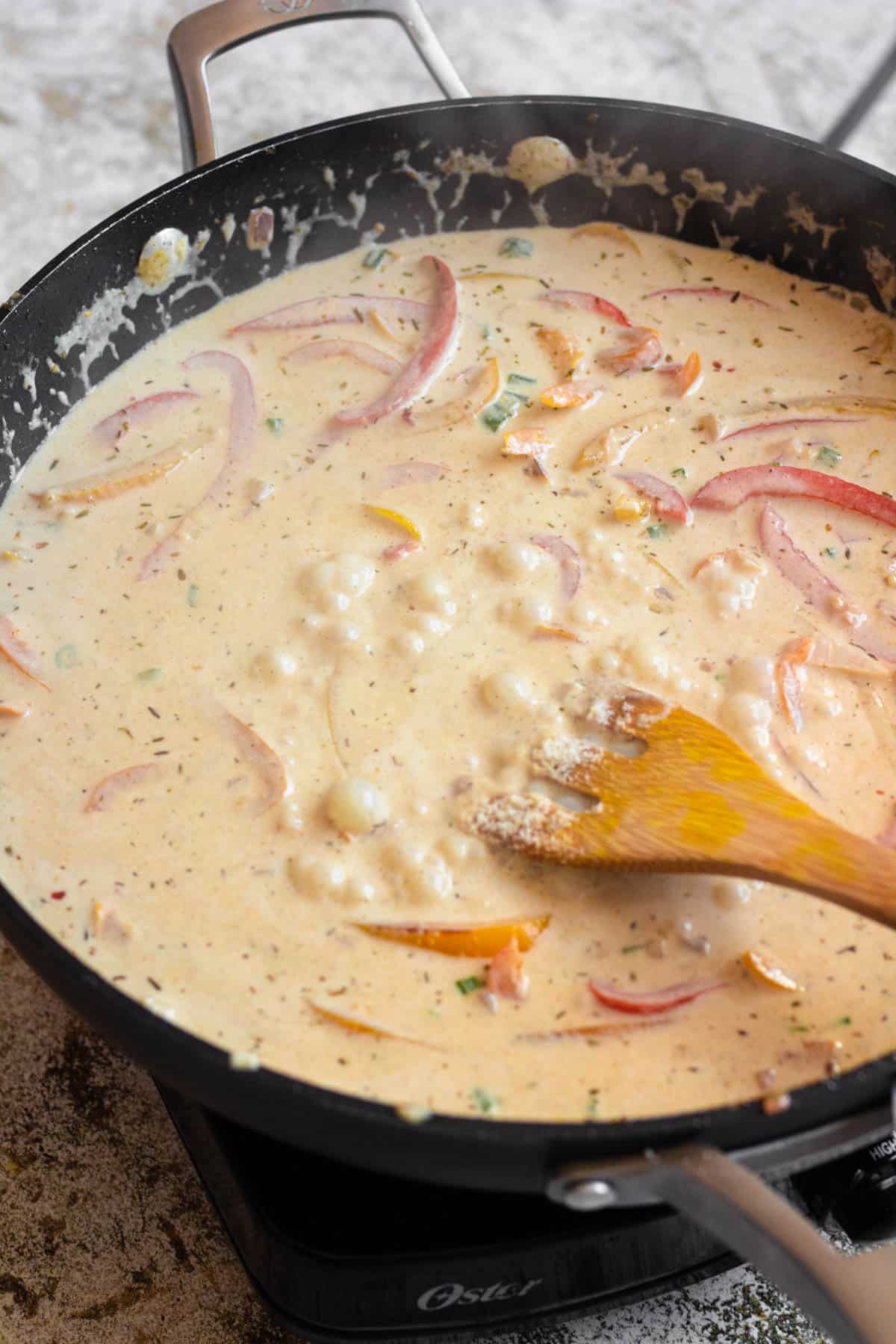 Thickened sauce in a skillet with a wooden spoon resting in it. 
