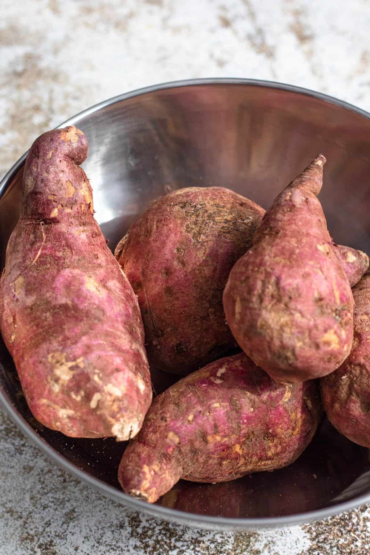 Bowl of purple skin white flesh sweet potatoes in a bowl. 