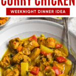 Pinterest image of a top view of a bowl of Jamaican curry chicken with a spoon rest in it.