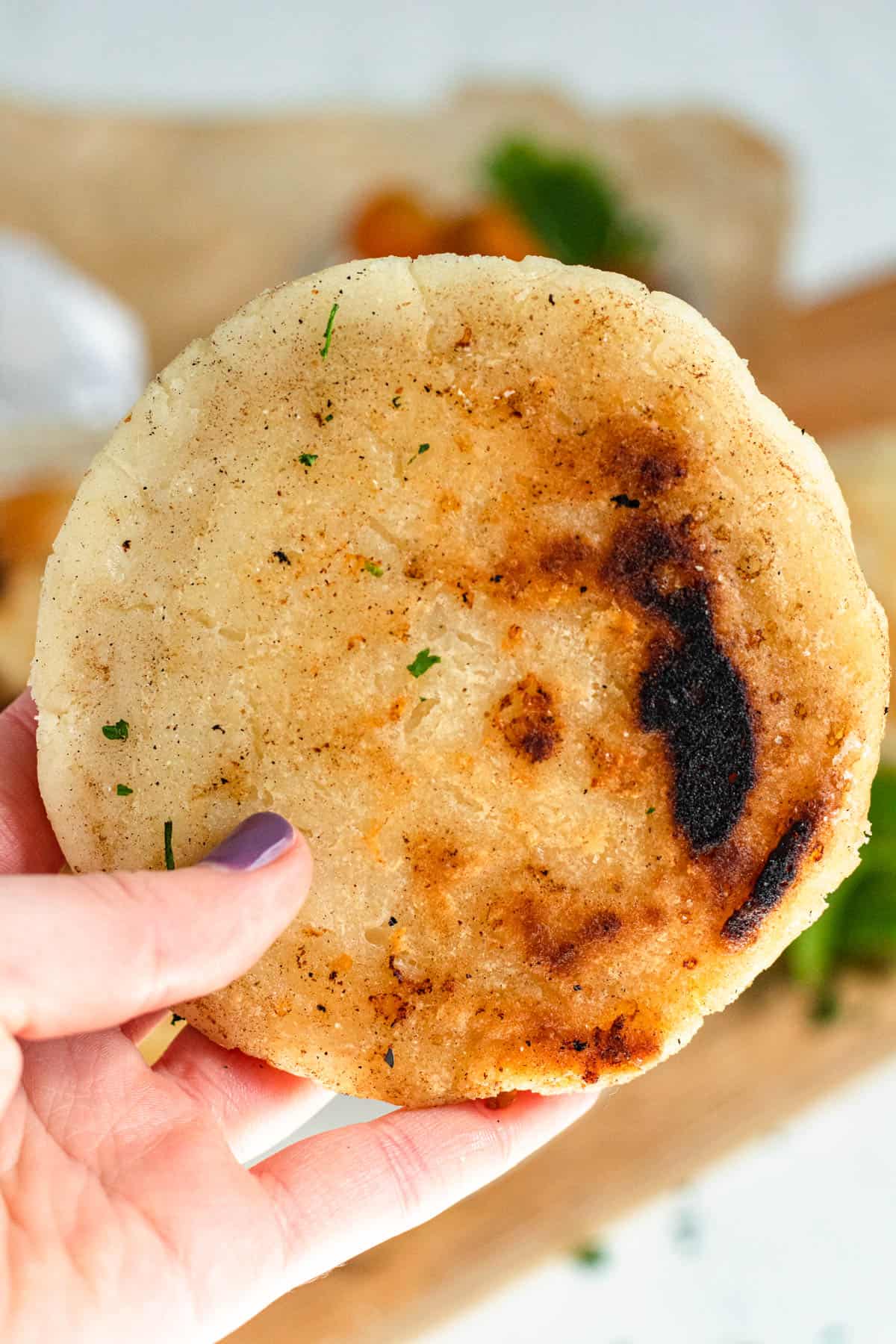 Hand holding up an arepa. 