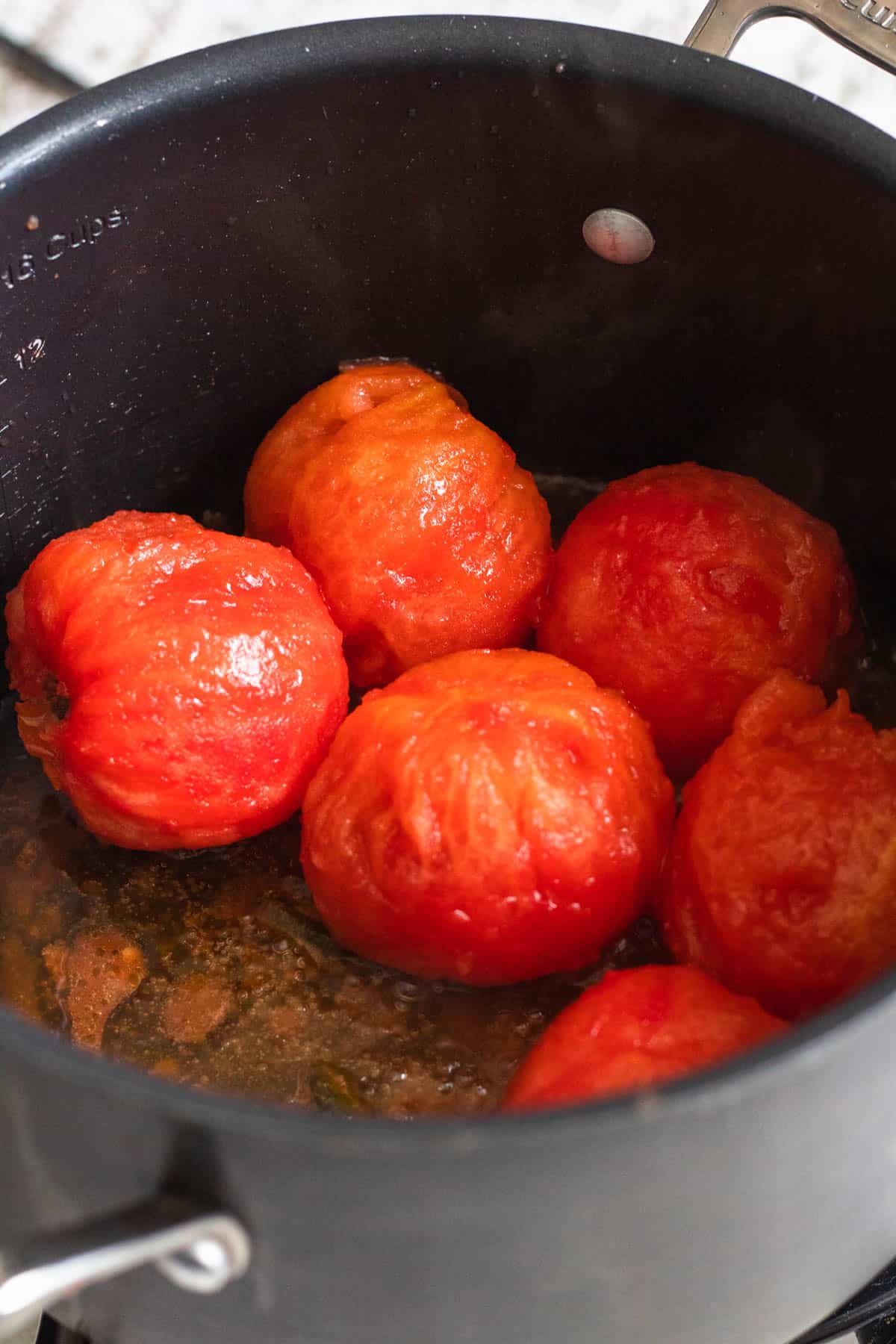 Peeled tomatoes cooking in a large pot.