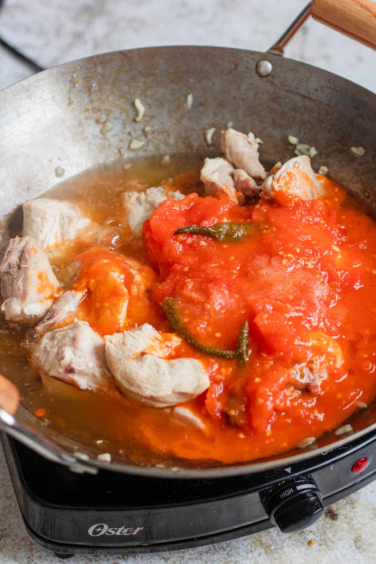 Chicken pieces added to the tomato sauce. 