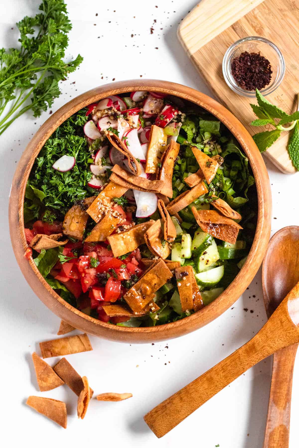 Lebanese Fattoush salad in a serving bowl with a wooden salad tongs resting next to it. 
