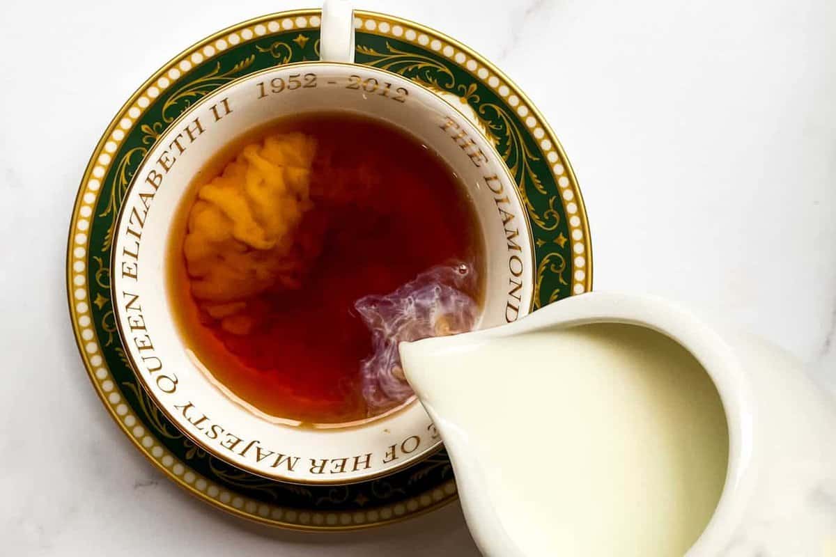 Creamer being poured into a cup of breakfast tea. 