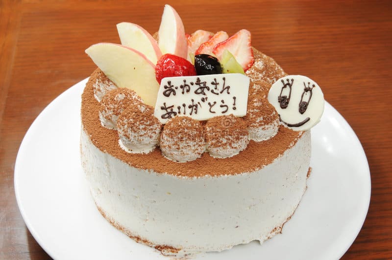 Cake with fresh fruit garnished on top and cocoa powder over the top. 