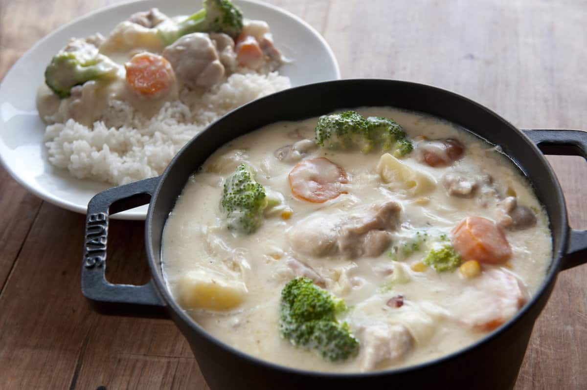 Dutch oven filled with cream stew, small bowl of white rice with cream stew next to it. 