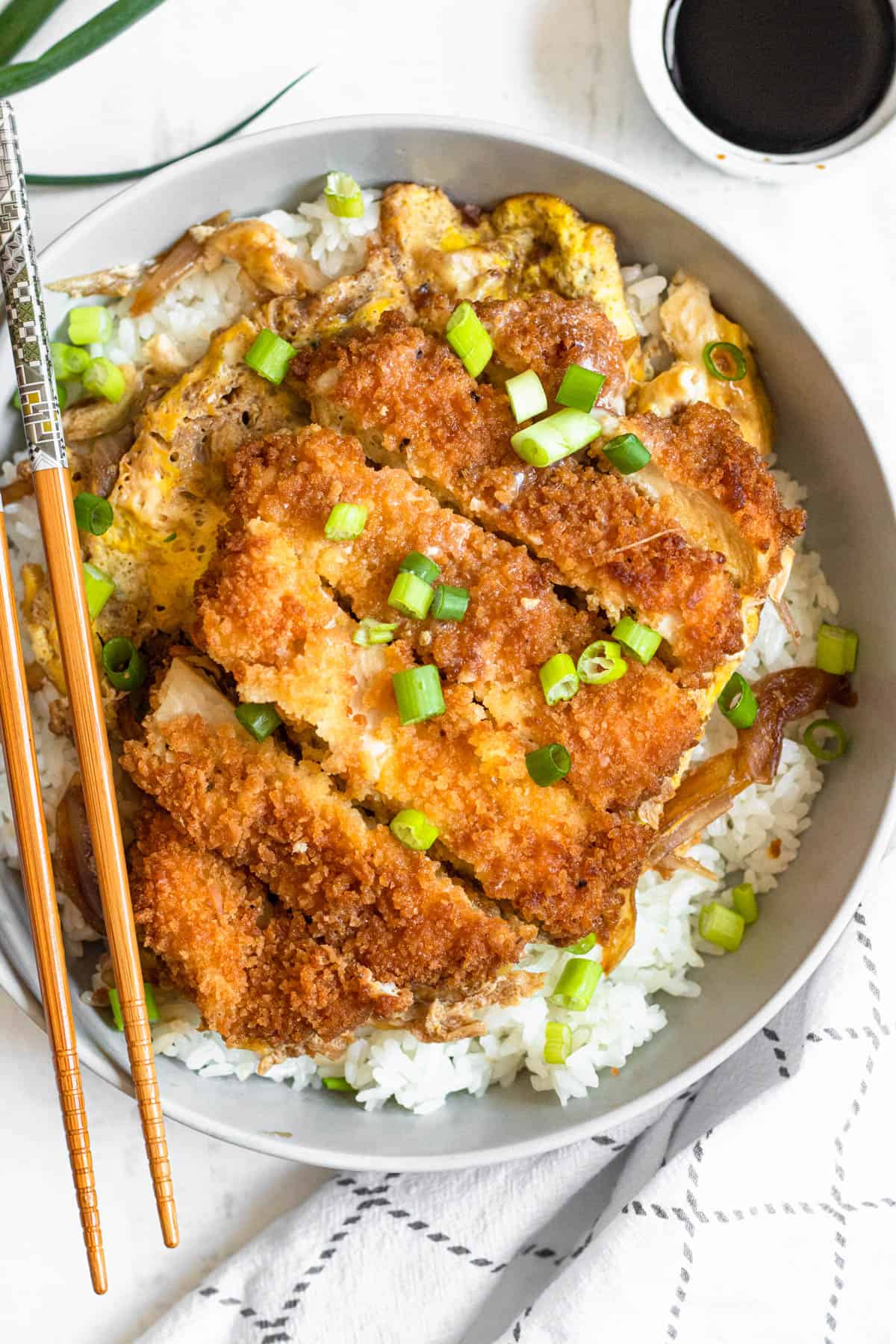 White rice in a bowl with Chicken katsudon served on top of it. 
