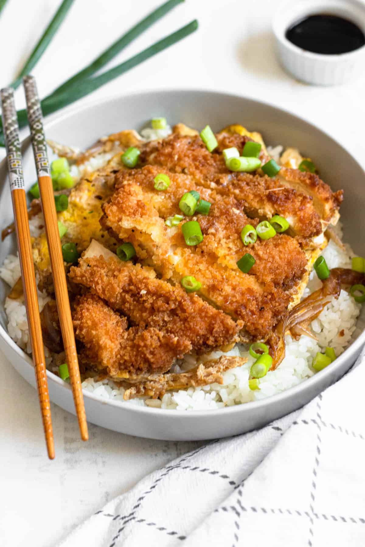 Chicken Katsudon served over a bed of white rice and sliced green onions garnished on the top. 