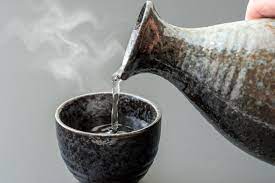 Warm saki being poured into a small cup. 