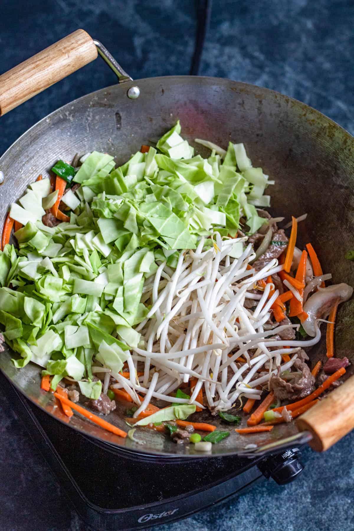 Bean sprouts and cabbage leaves added to the wok. 