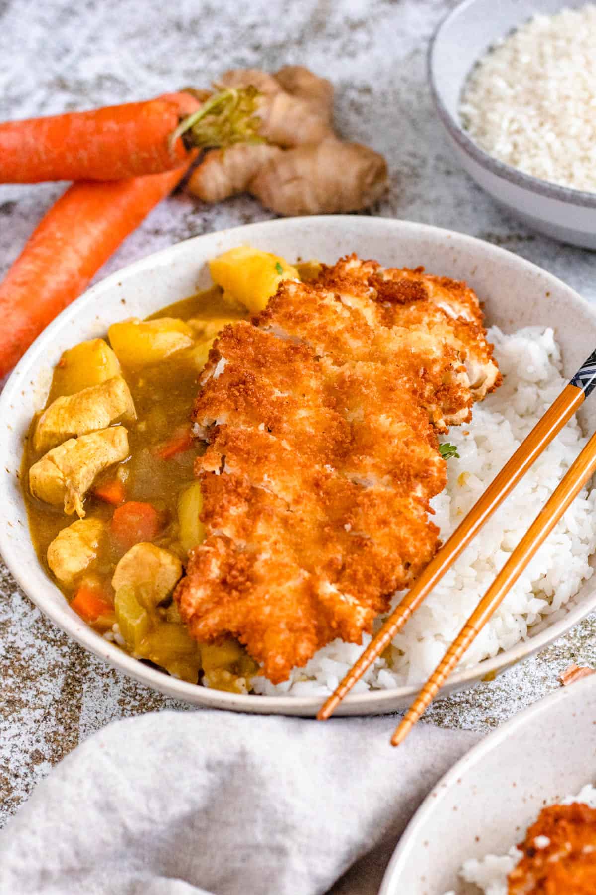 Chopsticks on the edge of a bowl served with chicken katsu curry recipe. 
