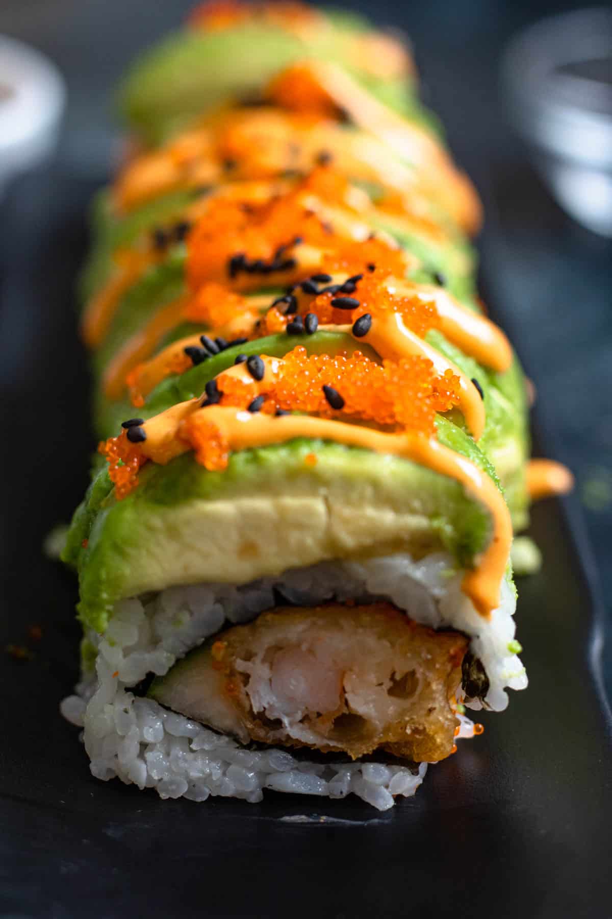 Tobiko and black sesame seeds added over sriacha mayo on a drago roll sushi recipe. 