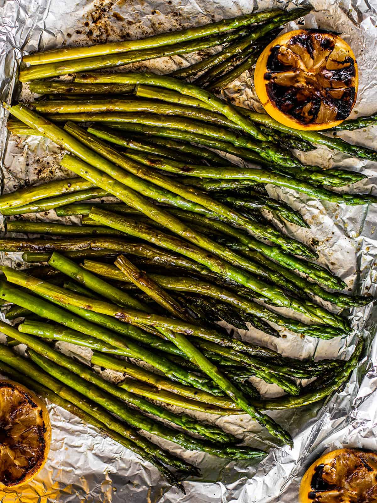 Grilled Asparagus with Grilled Lemon on a tin foil lined baking sheet.