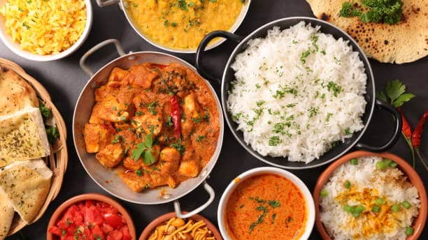 Indian curries in small bowls and a big pan of white rice. 