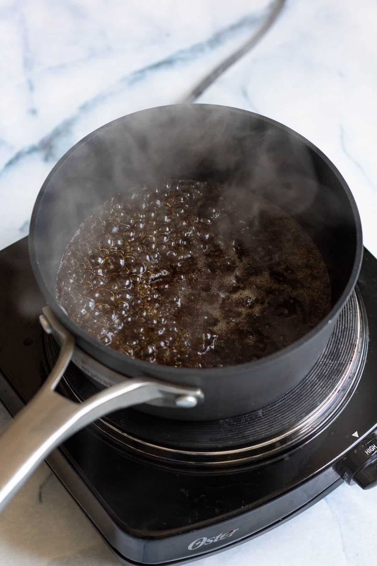 Tea leaves added to the boiling water in a saucepan. 
