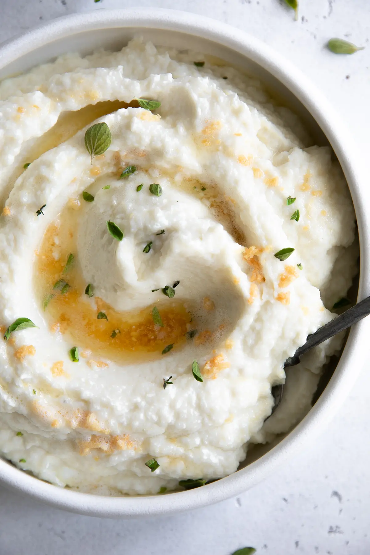 Mashed Cauliflower  in a serving bowl with herbs.