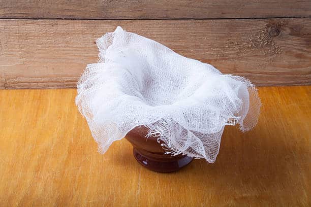 Bowl with cheesecloth tucked into it and overlapping over the sides. 