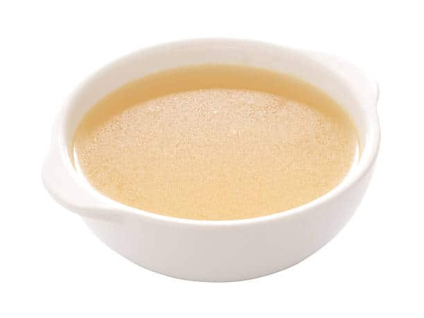 Small bowl of light colored chicken broth. 