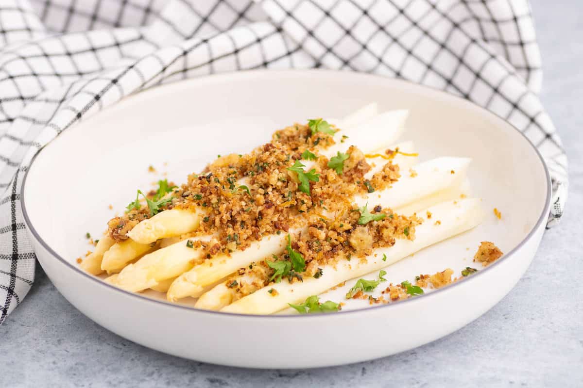 Herb Pangrattato on White Asparagus in a shallow bowl.