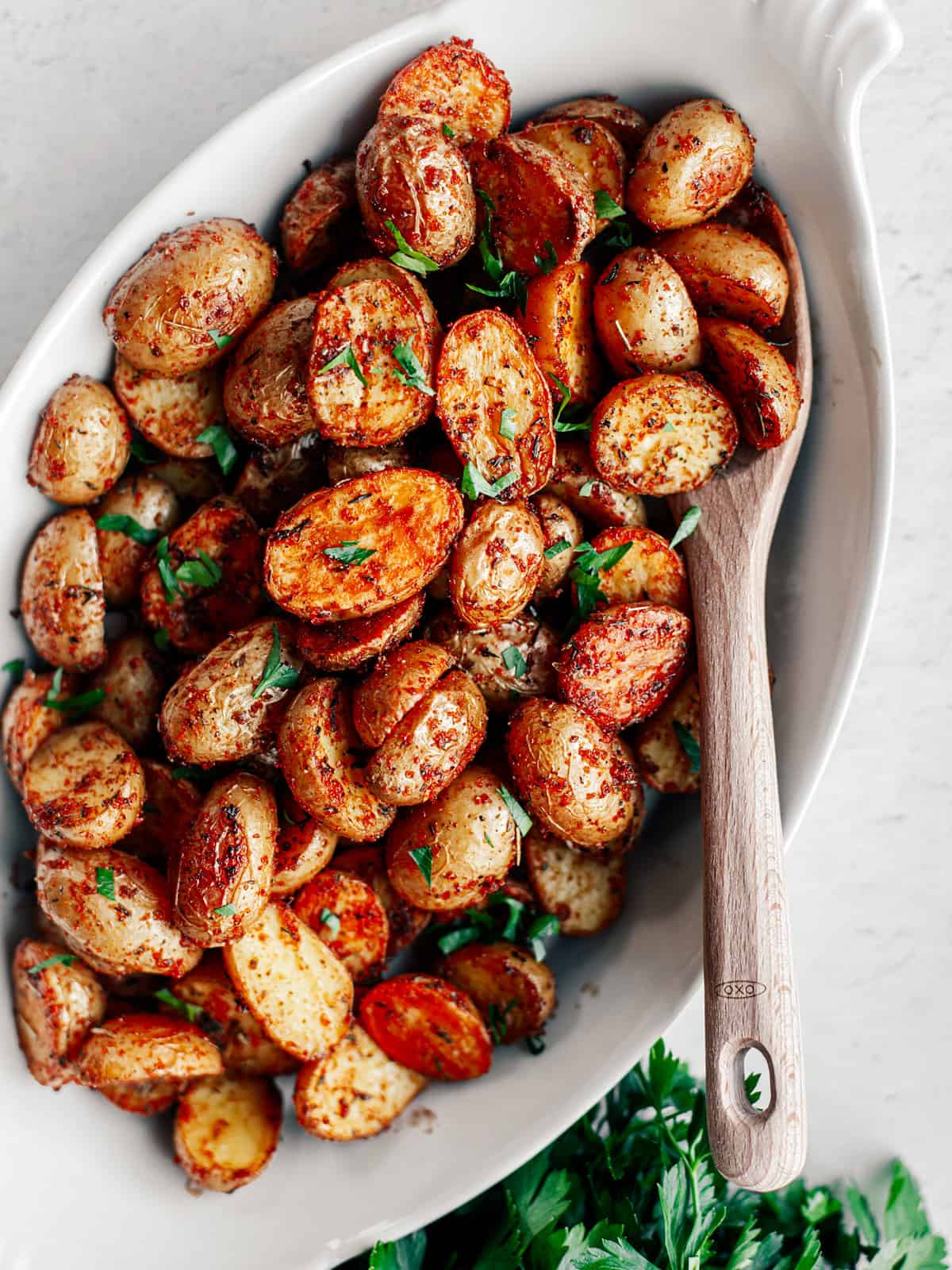 Crispy Roasted Mini Potatoes in a serving bowl with a wooden spoon.