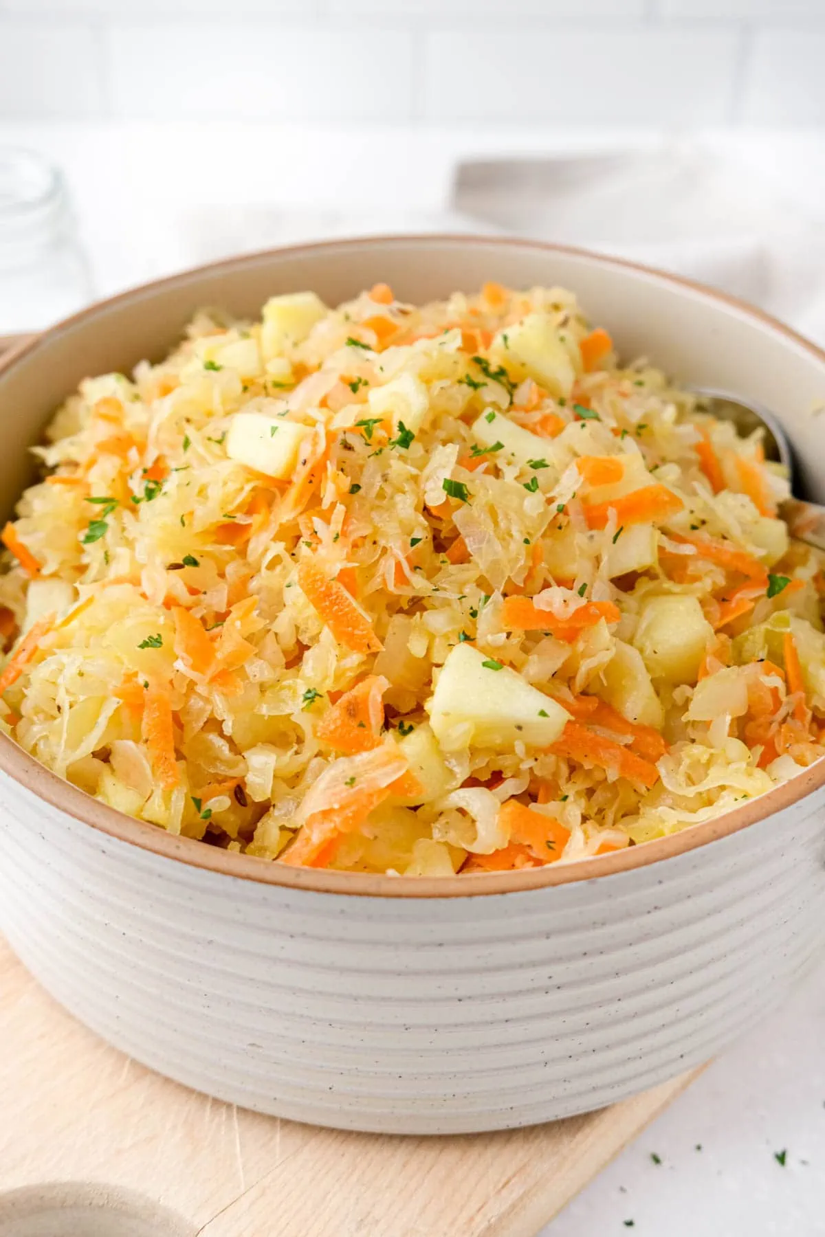 Easy sauerkraut salad in a bowl and a serving spoon resting in it. 
