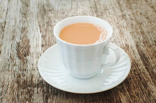 Plain white coffee mug served on a saucer with milk tea. 