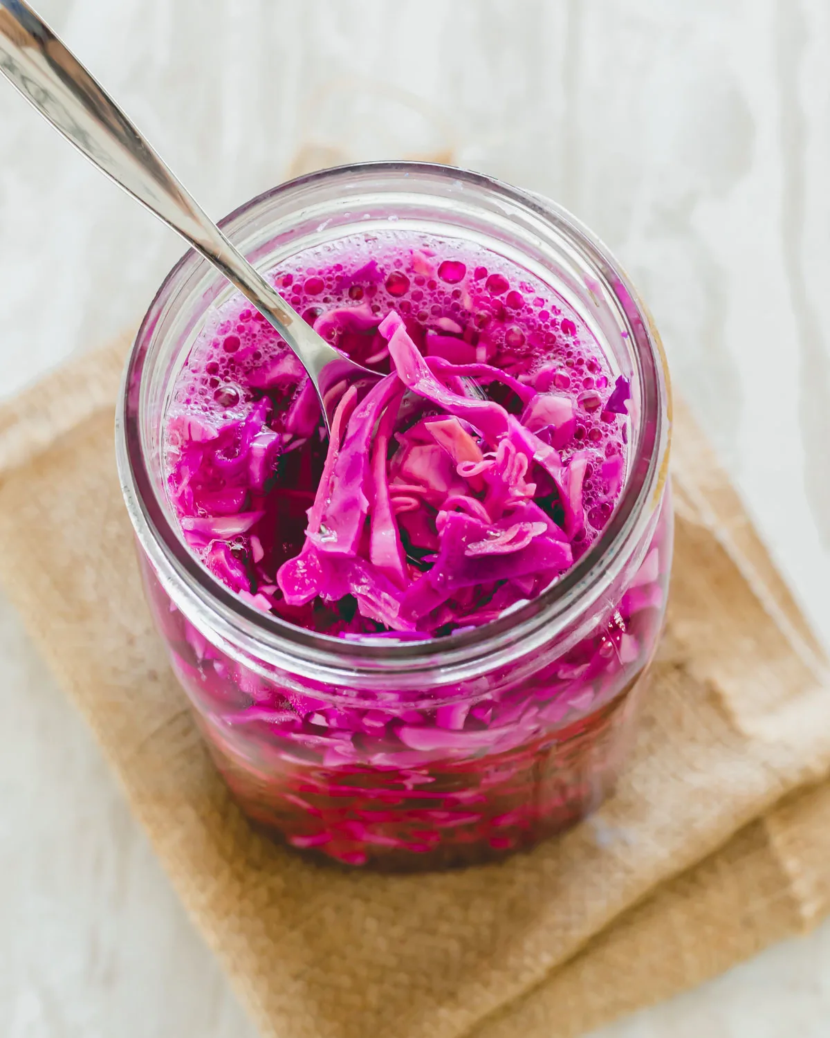 Spoon tucked into a mason jar of red cabbage sauerkraut.