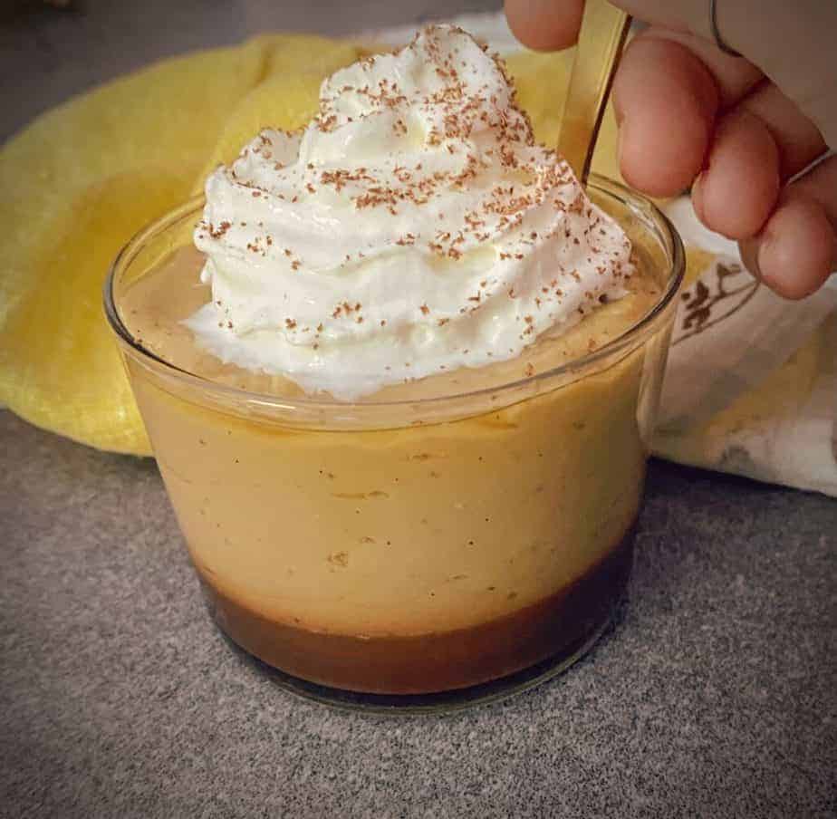 Banana pudding in a small glass cup with coffee rum fudge and whipped cream on top. 