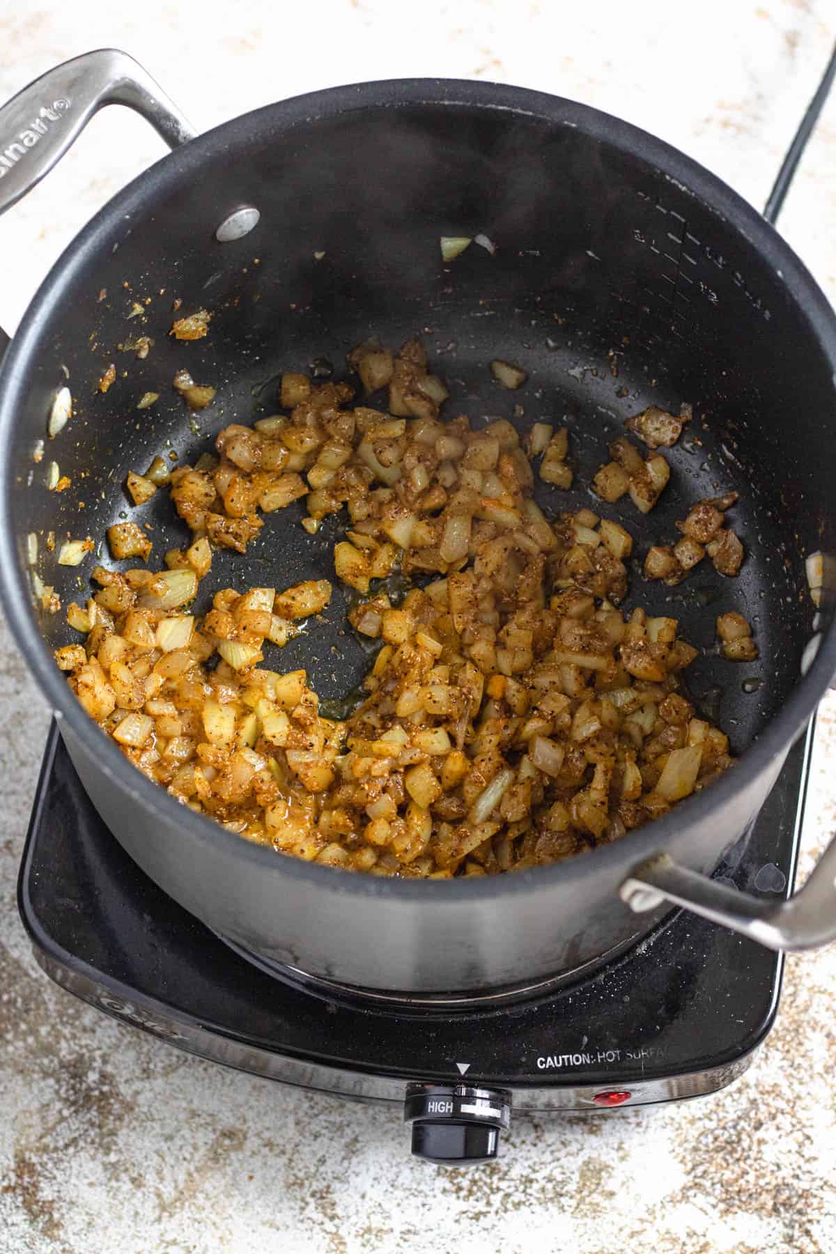Seasoned onions sauteing in a saucepan. 
