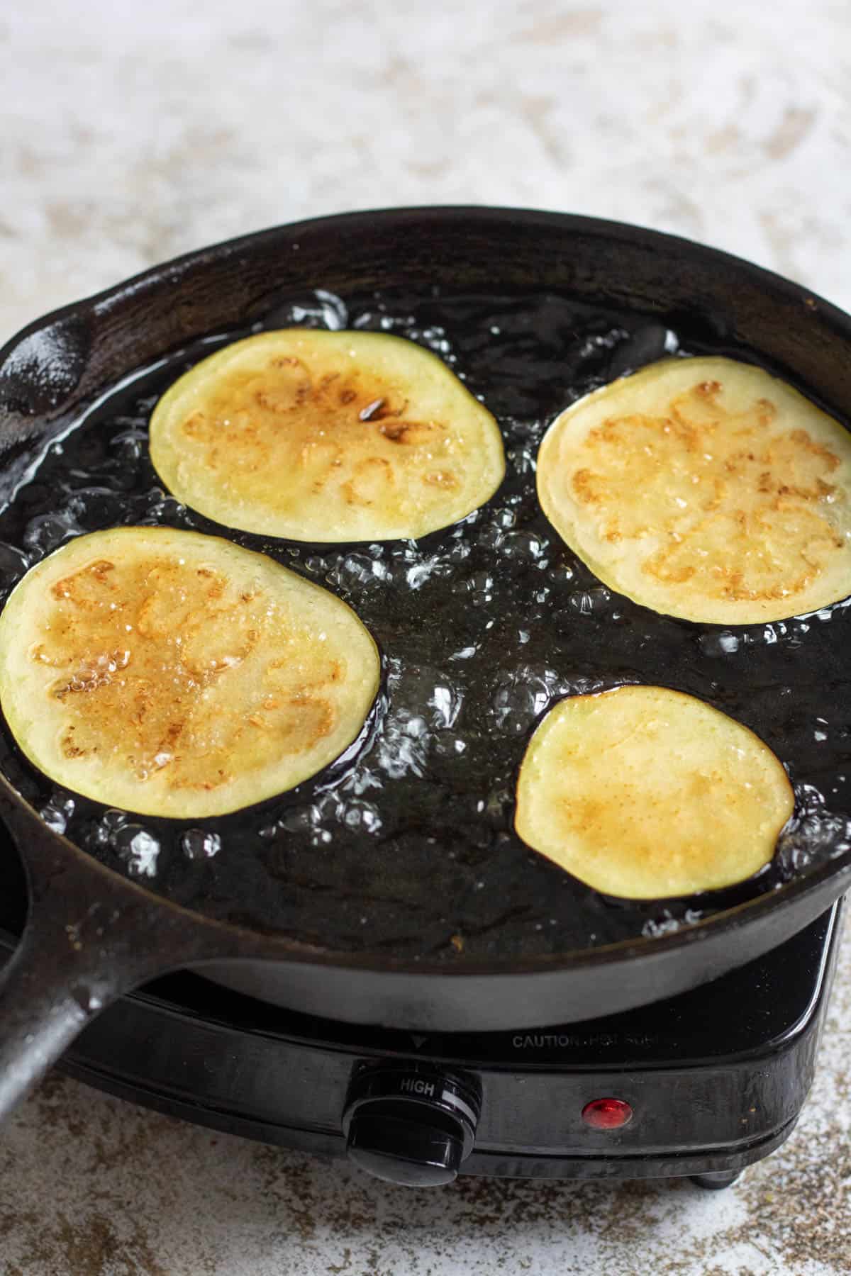 Sliced potatoes frying in a cast iron pan. 