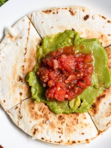 Sincronizada on a plate topped with guacamole and salsa.