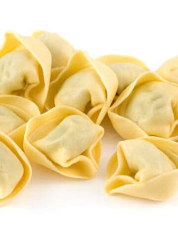 raw tortellini in a pile on a white background.