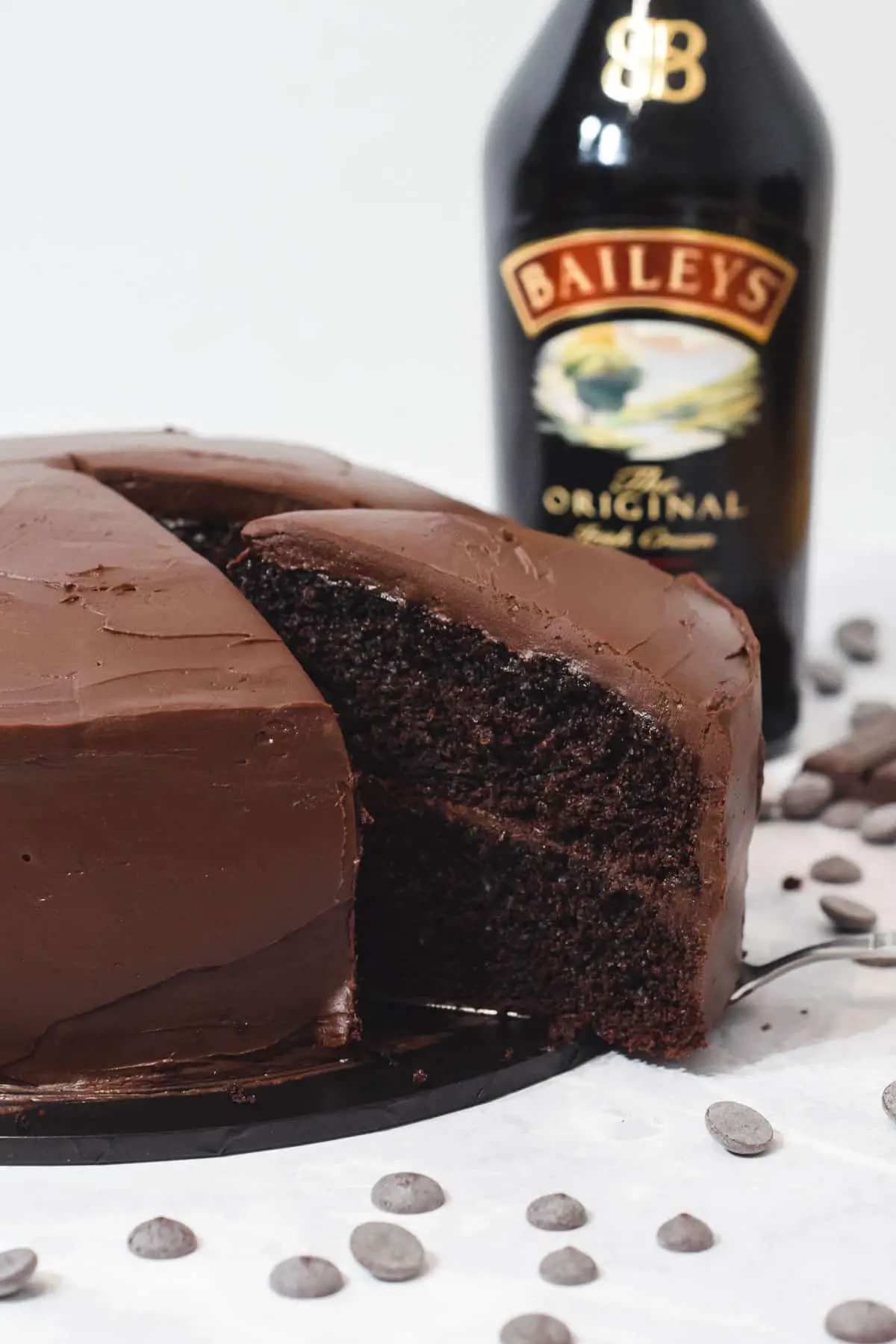 Baileys Chocolate mud cake with a slice being removed and a bottle of Irish cream next to it. 