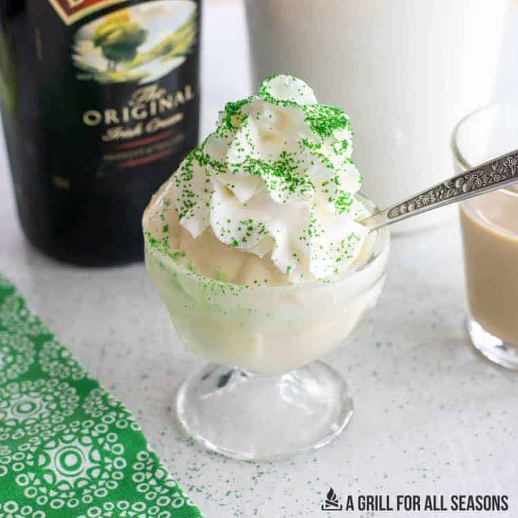 Small glass dish of baileys irish cream ice cream with green sprinkles on top and a spoon resting in it. 