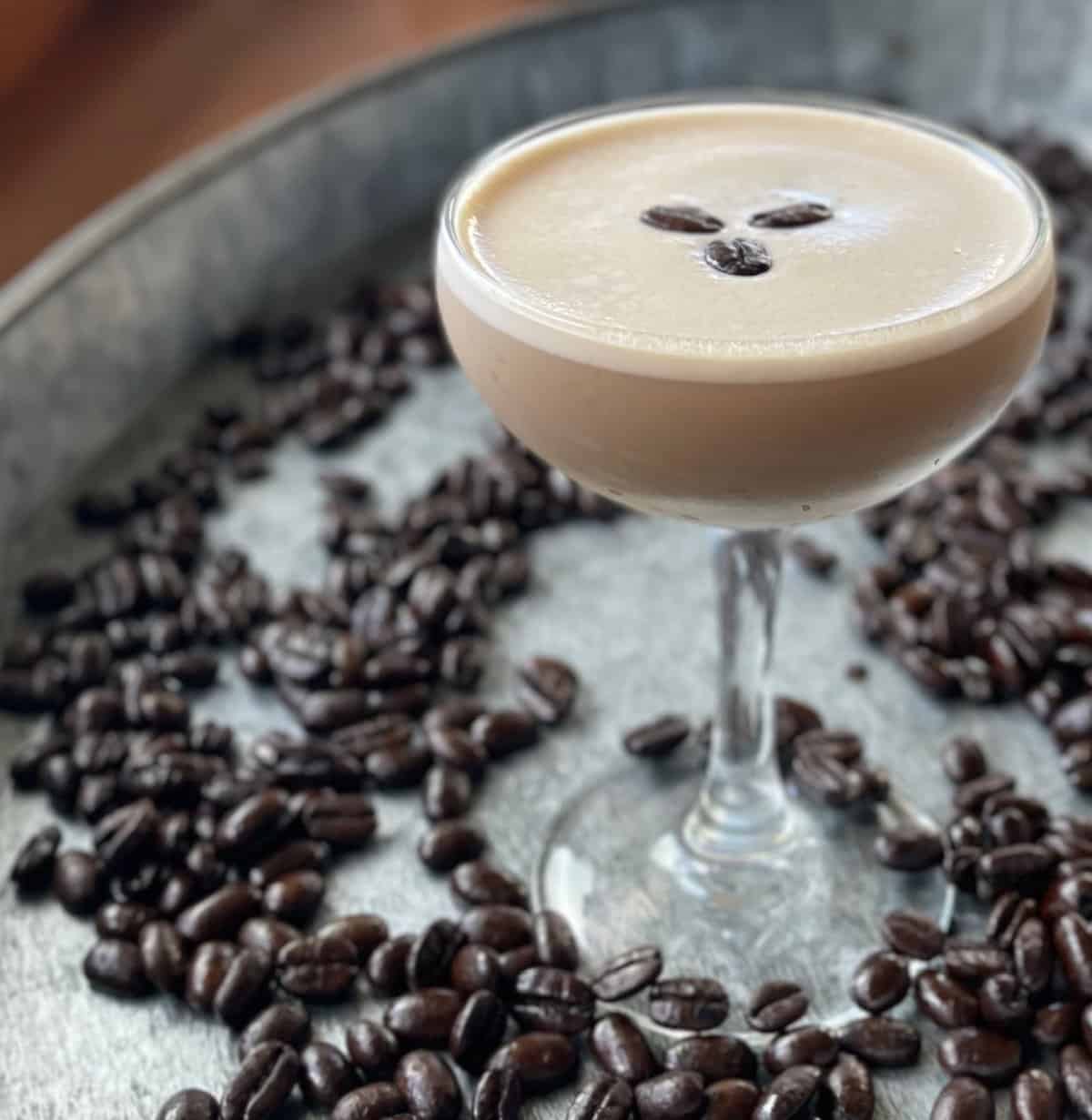 Espresso martini with baileys in a champagne flute with a couple espresso beans garnished over the top. 