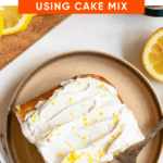 Pinterest image of a top view of a slice of lemon cake with Cool Whip on top and fresh lemon zest over the top and a fork resting on the side.