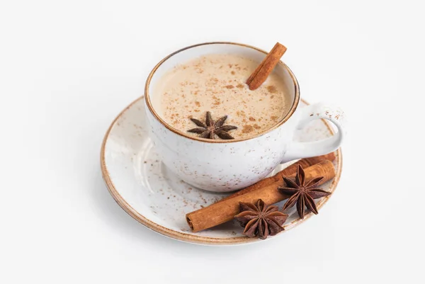 Chai latte on a sauce with cinnamon sticks and anise stars resting on the plate. 