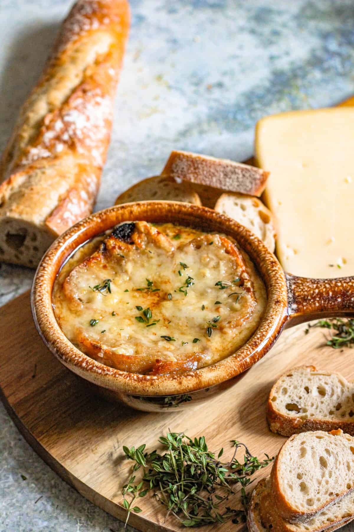 Crock filled with french onion soup with melted cheese over a slice of bread. 