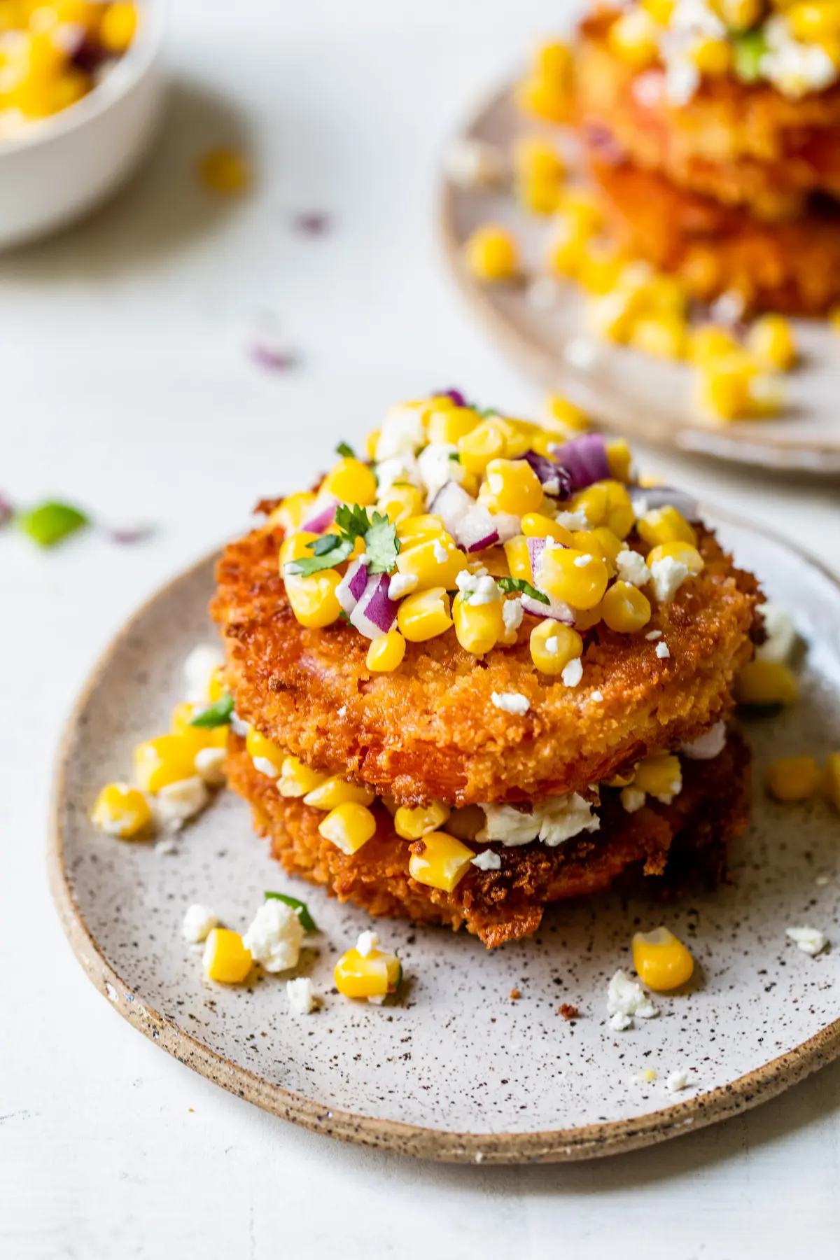 Stack of fried tomatoes with corn salsa in between the tomatoes and over the top. 