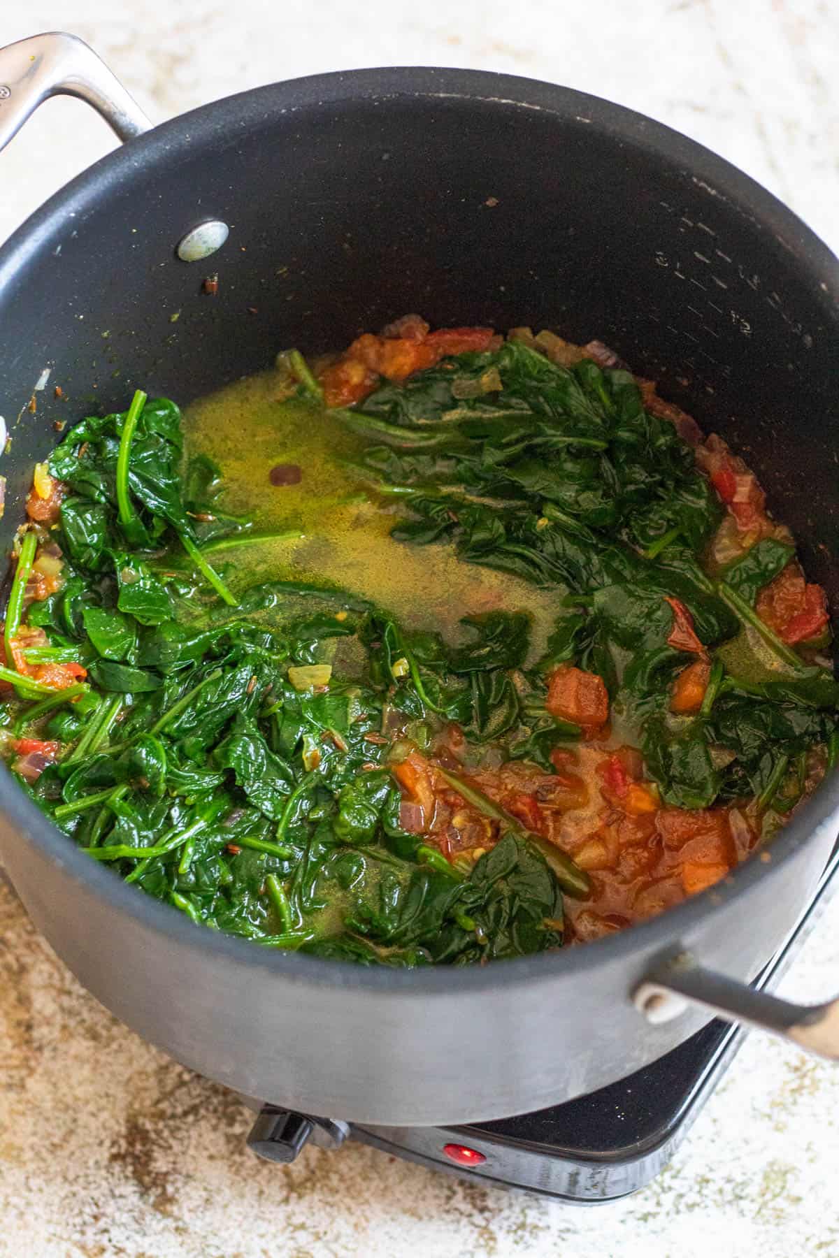 Spinach and tomatoes added to the saucepan. 