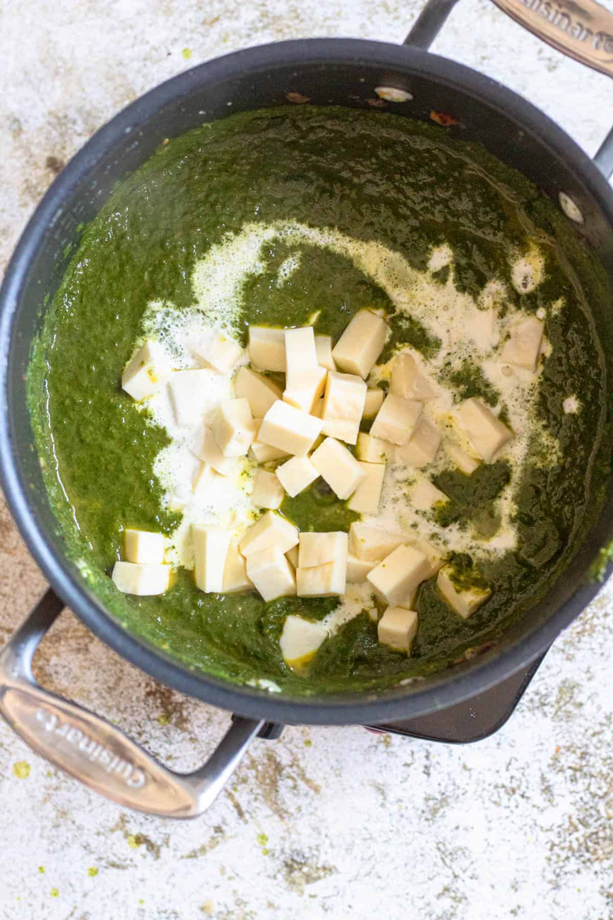 Paneer and heavy cream added to the palak mixture in a saucepan. 
