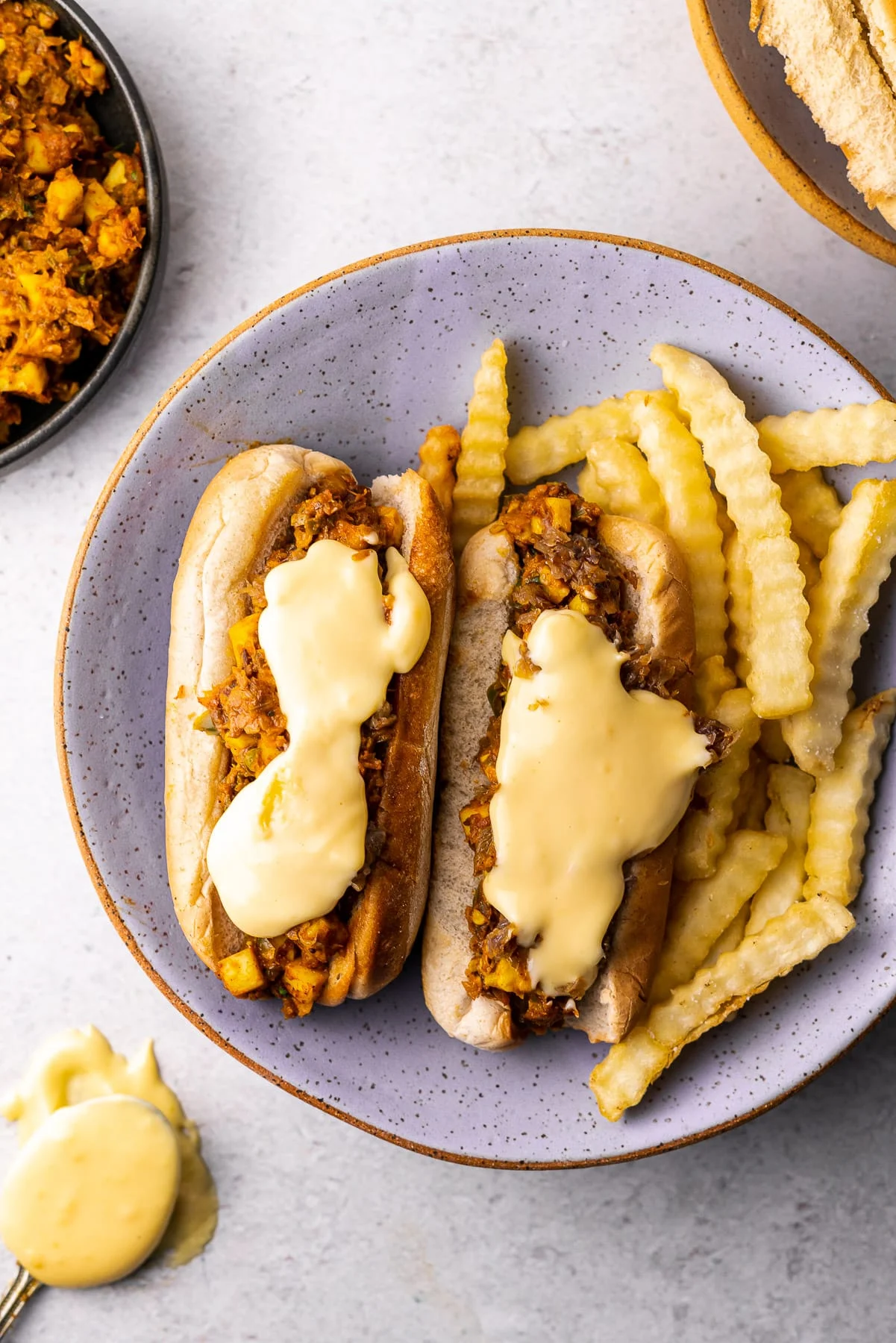 Paneer masala cheesesteak sandwiches served on a plate with a side of fries. 