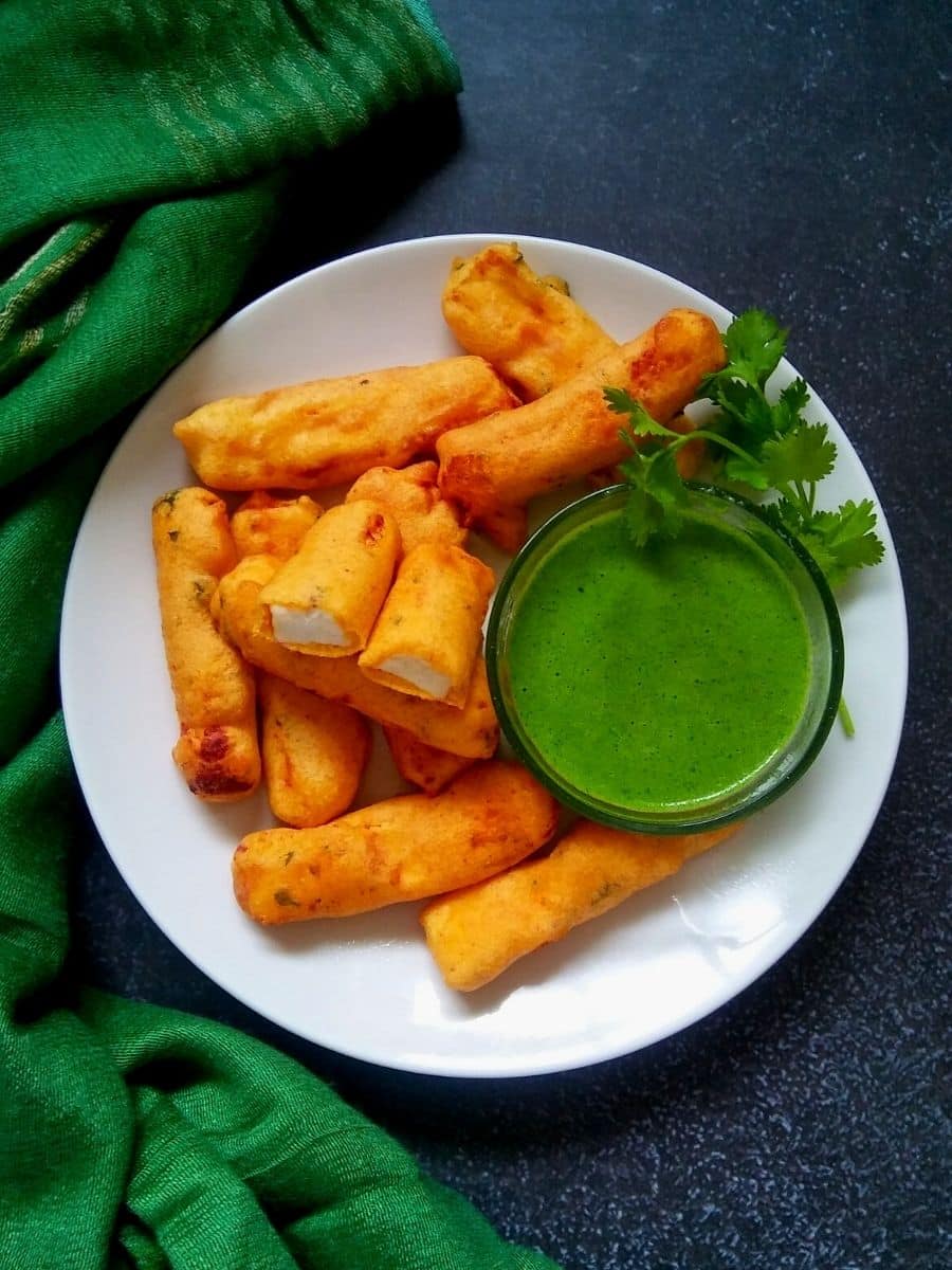 Paneer pakora served on a plate with dipping sauce. 