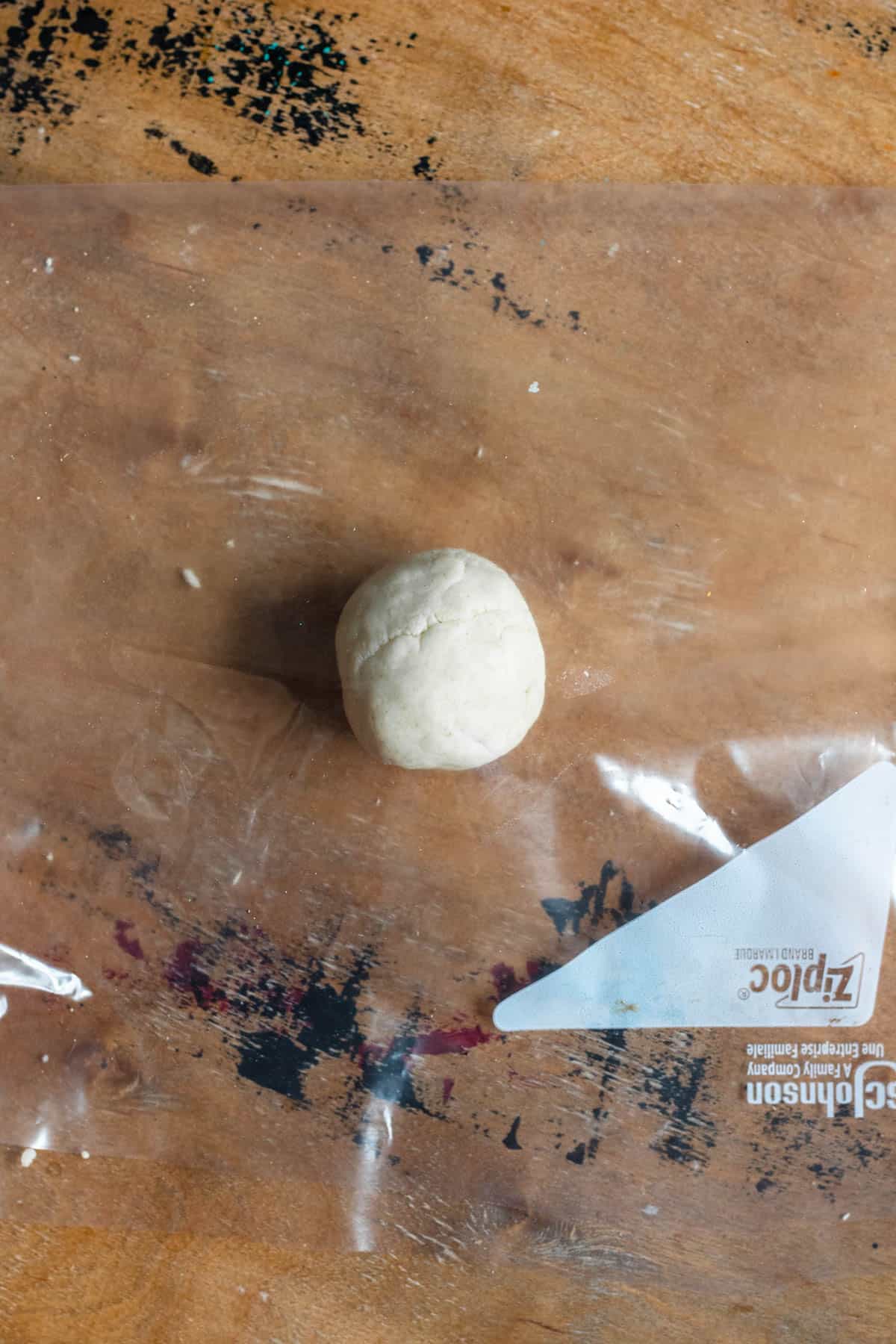 Picadita dough formed into a ball with a ziploc bag placed on top of it. 