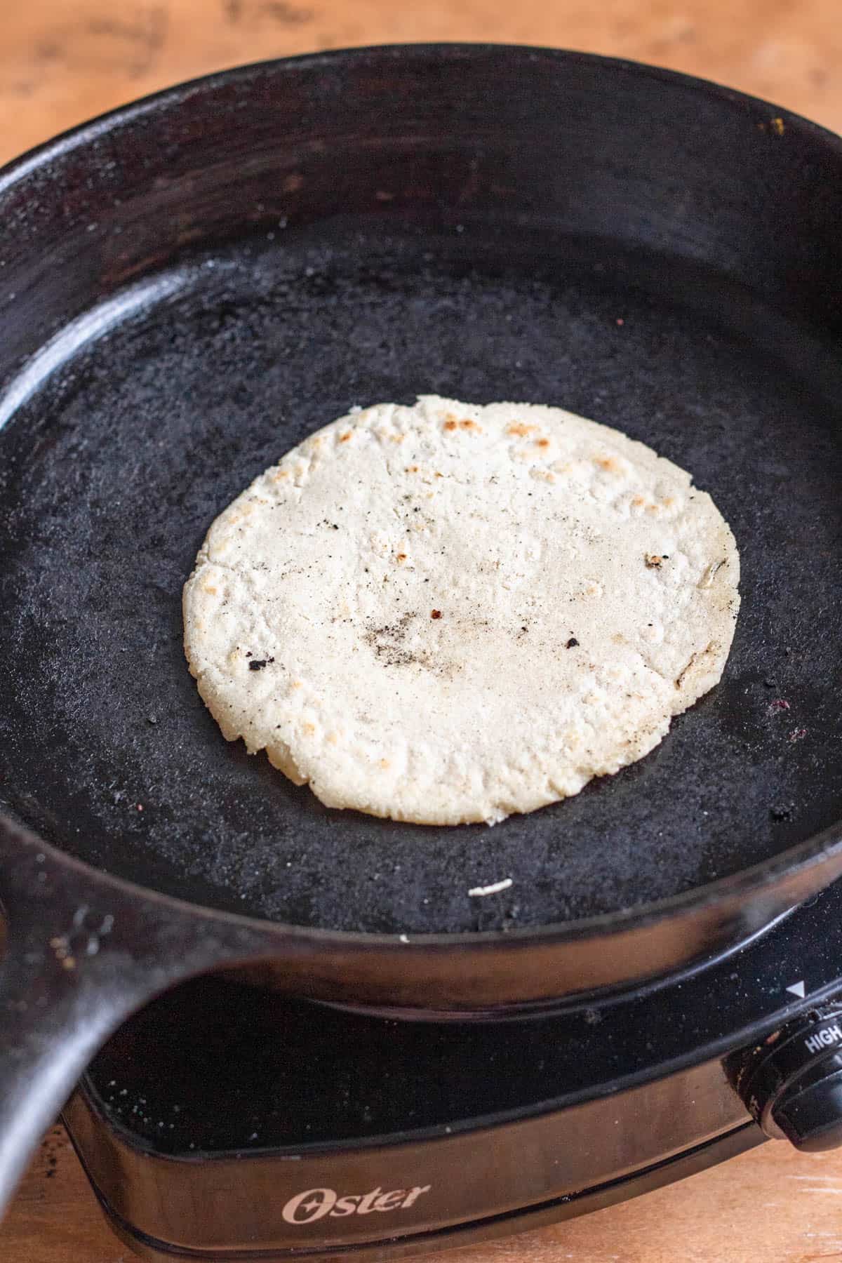 Picadita dough flipped over to cook the other side of the dough in the cast iron pan. 