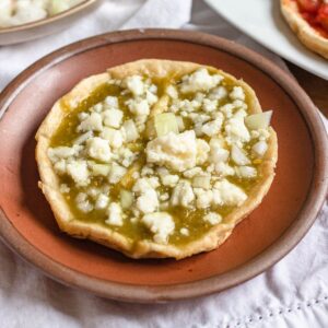 Picaditas topped with salsa verde and with crumbled queso fresco on top.