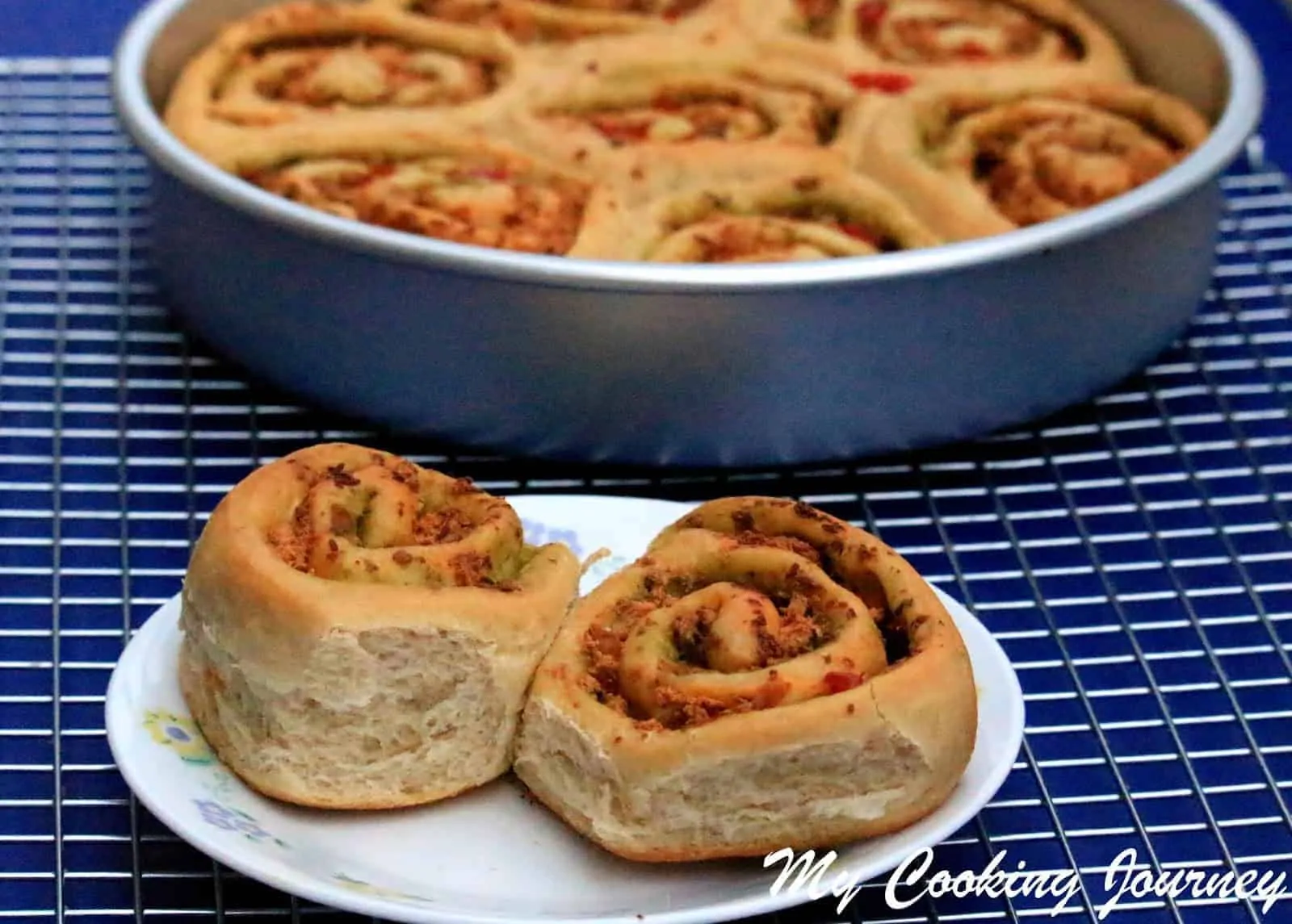 Savory swirl buns with basil pesto and paneer bell on a plate next to the baking dish. 