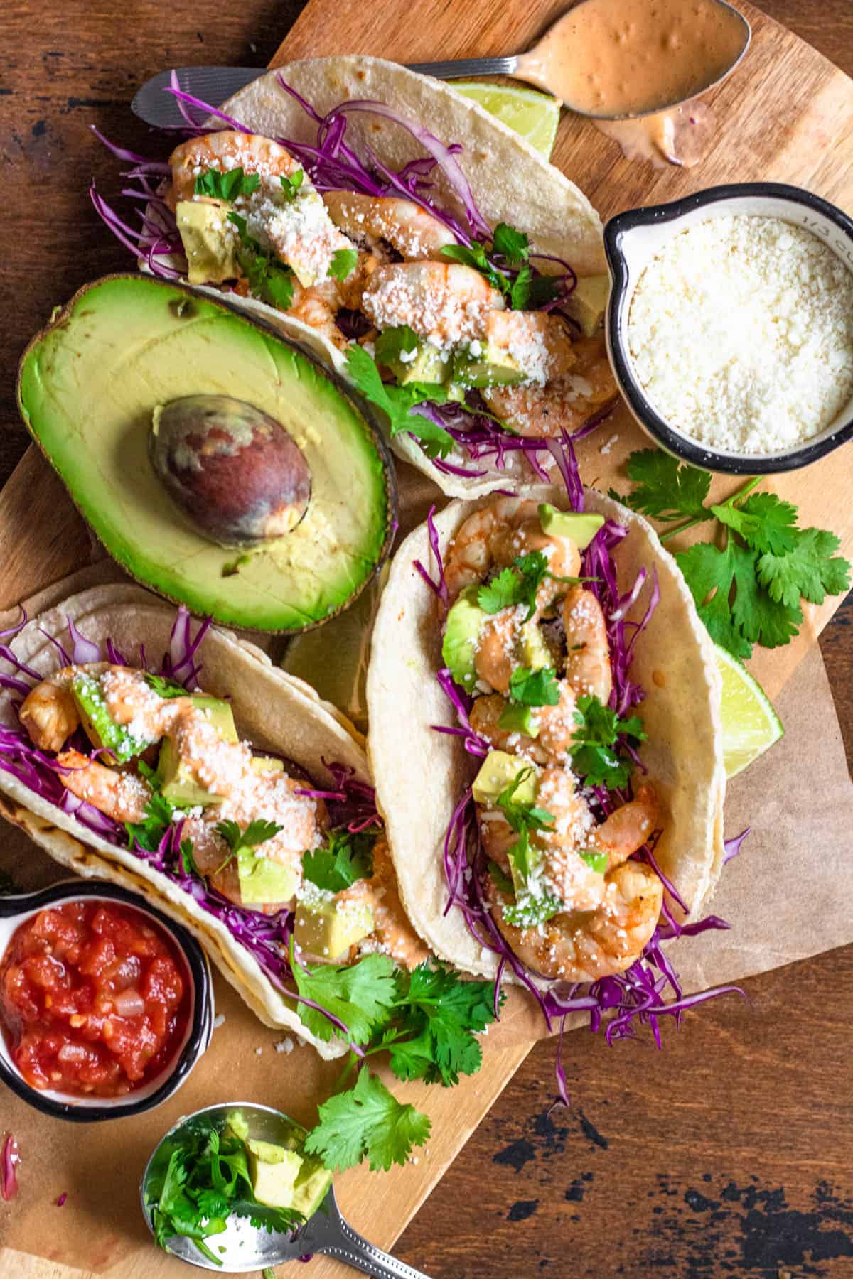 3 shrimp corn tacos with red cabbage, avocado chunks and cotija cheese