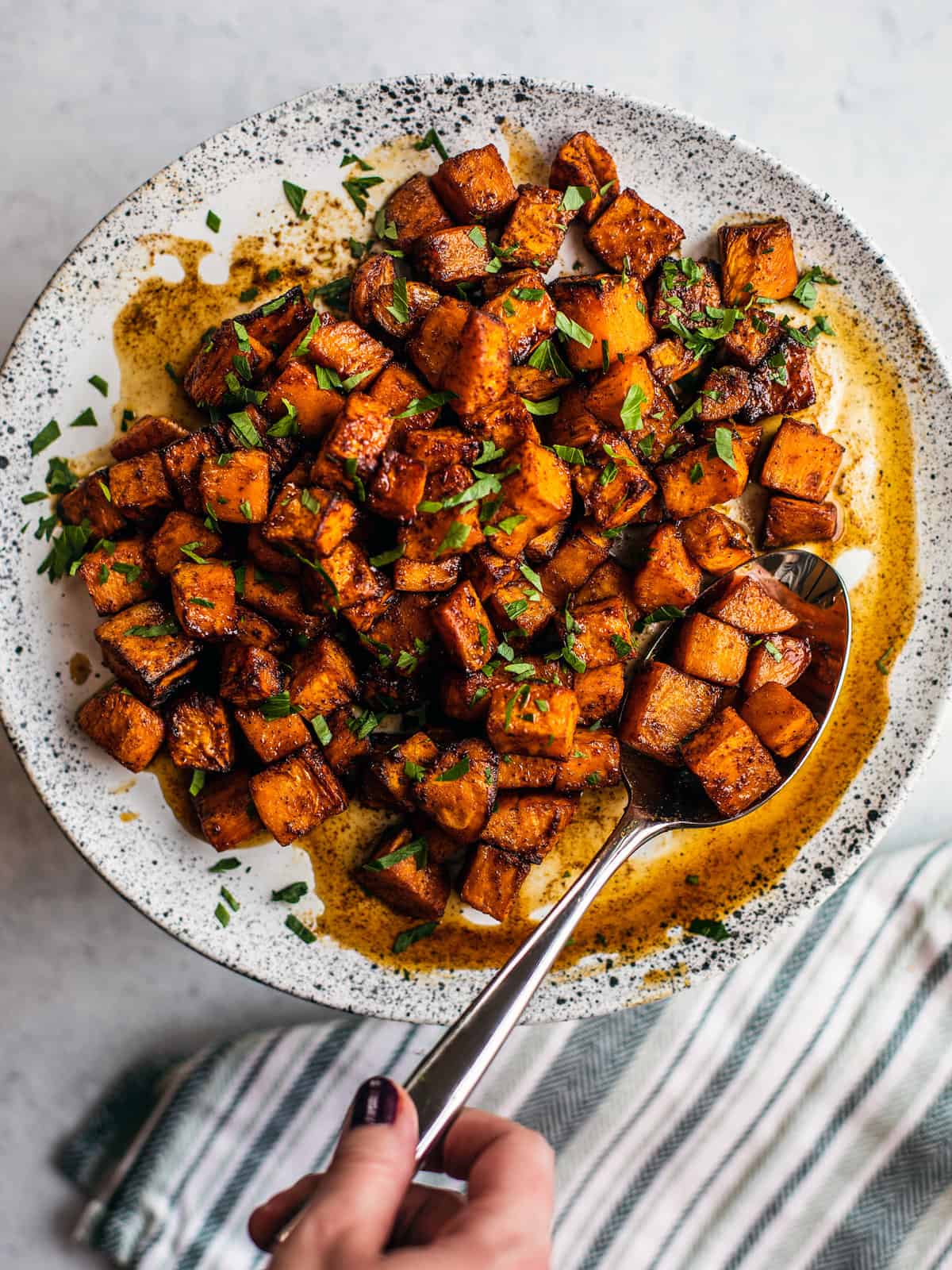 Plate full of honey lime air fryer sweet potato chunks with a serving spoon resting on the plate. 